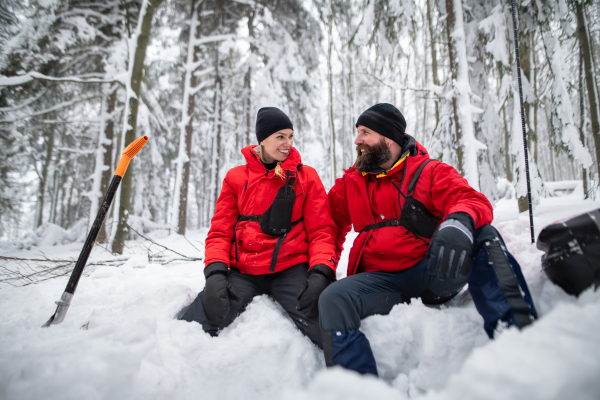 Mountain rescue service on operation outdoors in winter in forest, digging snow with shovels. Avalanche concept.