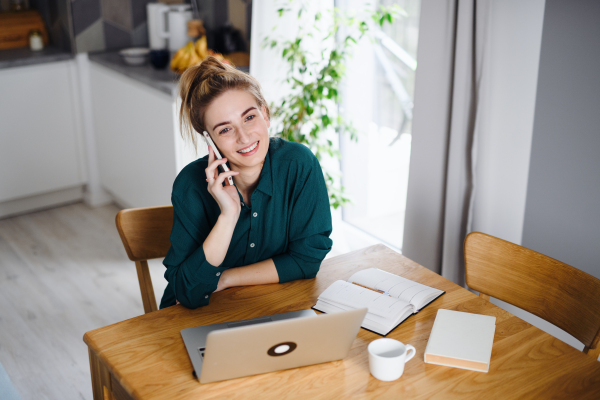 A young woman student with laptop and smartphone at home, home office and learning.