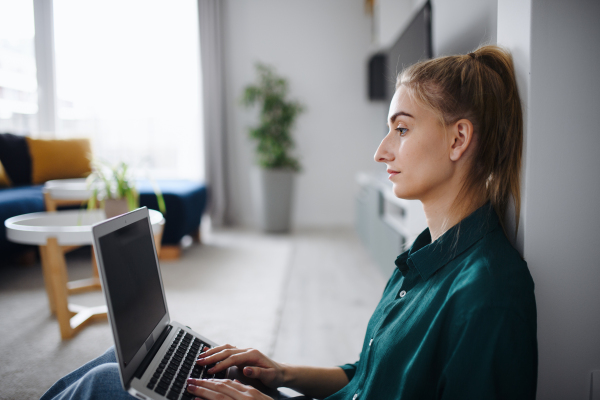 A young woman student with laptop at home, home office and learning.