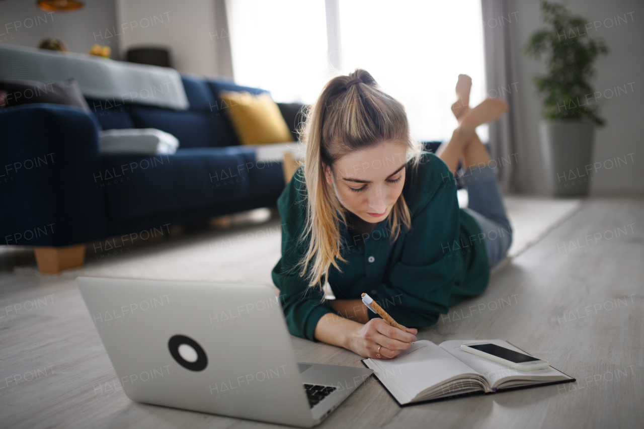 A young woman student with laptop and smartphone at home, home office and learning.