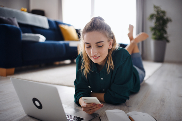 A young woman student with laptop and smartphone at home, home office and learning.