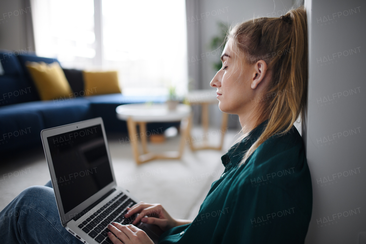 A tired young woman student with laptop at home, home office and learning.