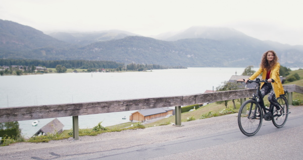 Portrait of young woman tourist on a hiking trip in nature, cycling on bicycle.