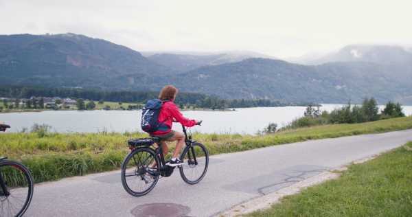 Happy senior pensioner couple bikers with bicycles cycling in nature, cycling trip concept.