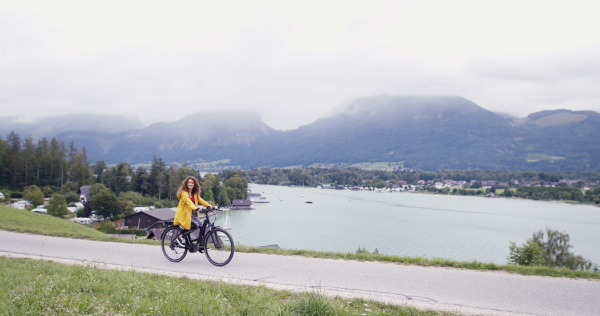 Portrait of young woman tourist on a hiking trip in nature, cycling on bicycle.