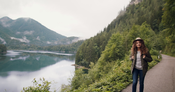 Happy young woman tourist with a backpack on a hiking trip in nature, walking.