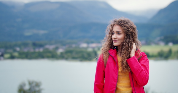 Happy young woman tourist with a backpack on a hiking trip in nature, walking.