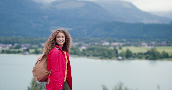 Happy young woman tourist with a backpack on a hiking trip in nature, walking.