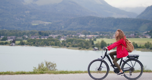 Portrait of young woman tourist on a hiking trip in nature, cycling on bicycle.