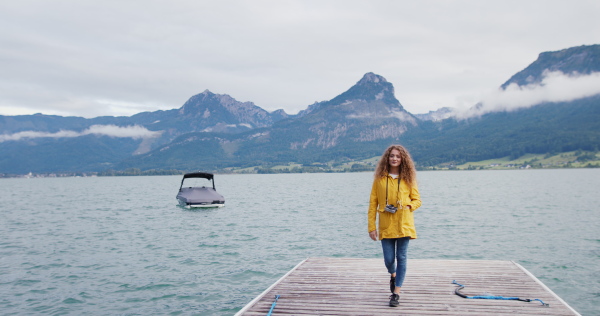 Portrait of young woman tourist standing on a pier by lake.