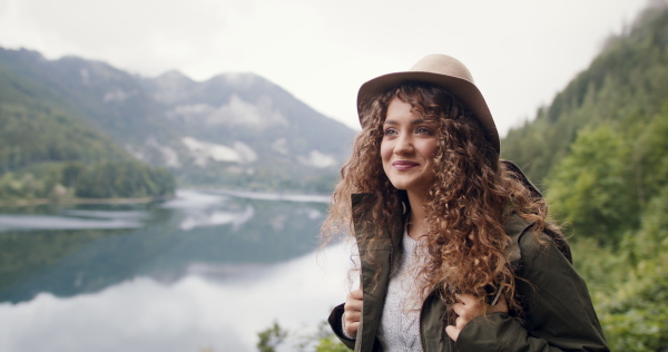 Happy young woman tourist with a backpack on a hiking trip in nature, walking.