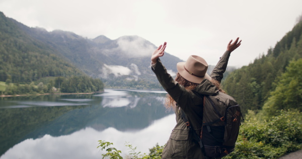 Happy young woman tourist with a backpack on a hiking trip in nature, walking.