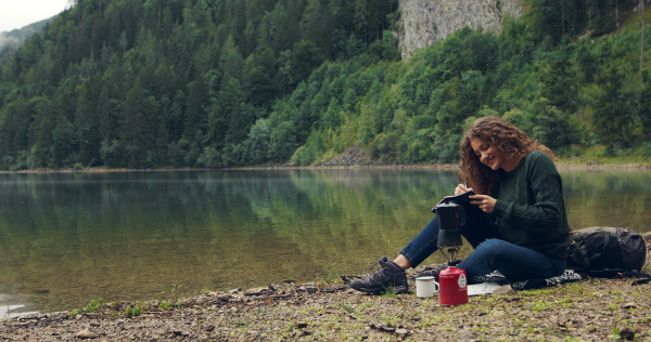 Young woman tourist with a map on a hiking trip in nature, sitting and resting.