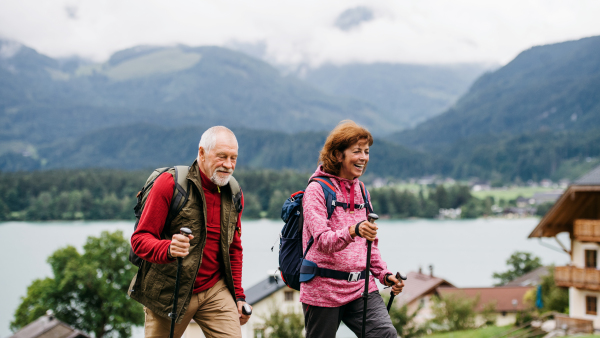 A senior pensioner couple with nordic walking poles hiking in nature.