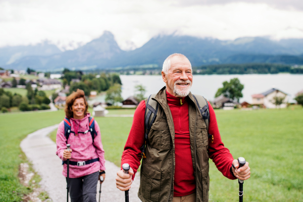 A senior pensioner couple with nordic walking poles hiking in nature, talking.