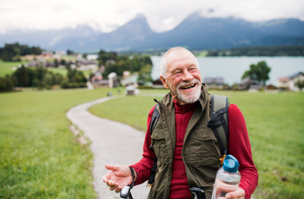 A senior man with nordic walking poles hiking in nature, resting.