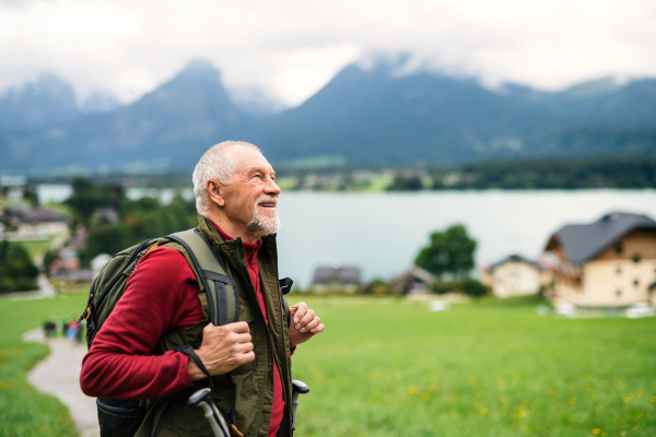 Happy senior man with backpack hiking in nature, resting. Copy space.