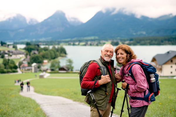 A senior pensioner couple with nordic walking poles hiking in nature, standing.