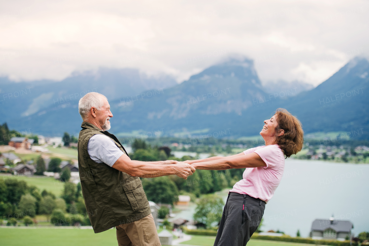 An active senior pensioner couple hiking in nature, holding hands.