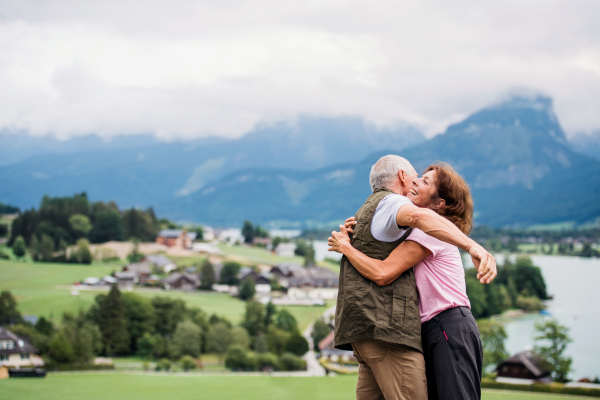 An active senior pensioner couple hiking in nature, hugging. Copy space.