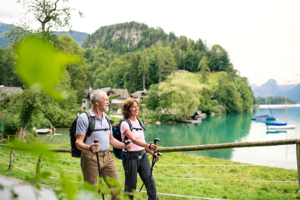 A happy senior pensioner couple with nordic walking poles hiking in nature.