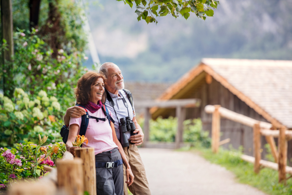 A happy senior pensioner couple with binoculars hiking, resting. Copy space.