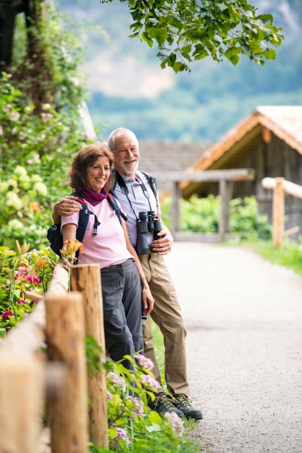 A happy senior pensioner couple with binoculars hiking, resting. Copy space.