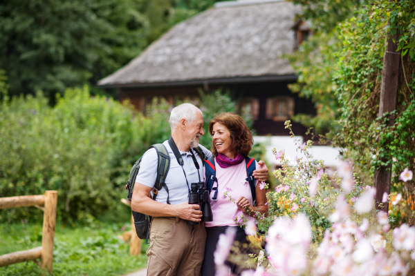 A happy senior pensioner couple with binoculars hiking, resting. Copy space.