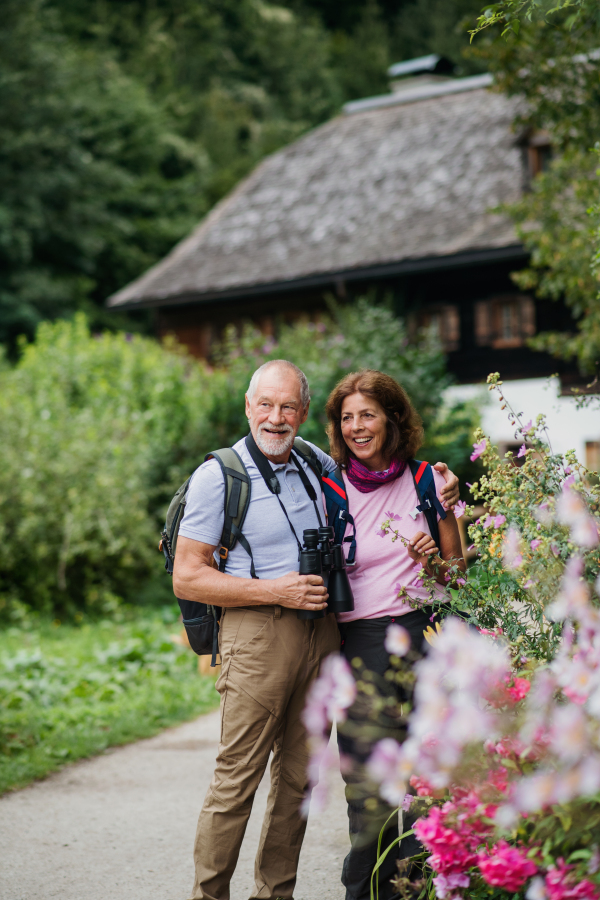 A happy senior pensioner couple with binoculars hiking, resting. Copy space.