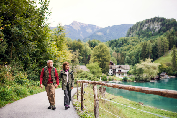 An active senior pensioner couple hiking in nature, holding hands.