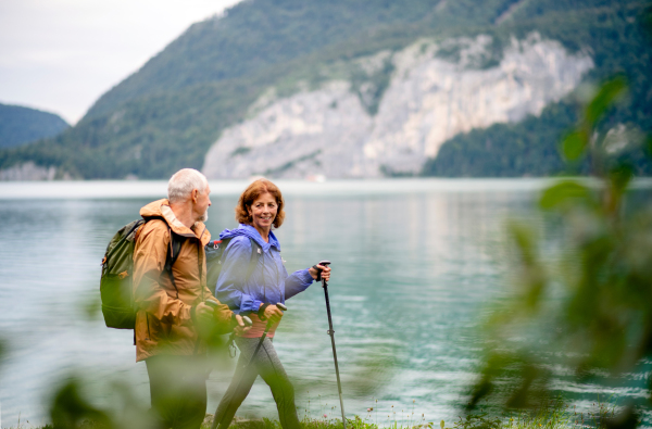 A senior pensioner couple hiking by lake in nature, talking. Copy space.