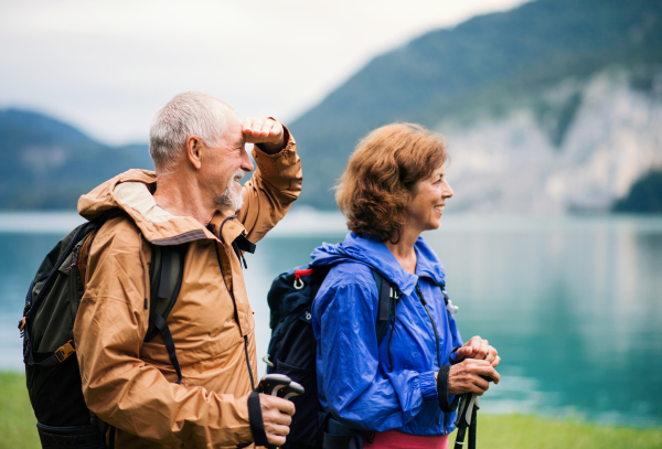 A senior pensioner couple hiking by lake in nature, resting.