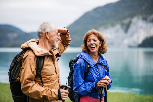 A senior pensioner couple hiking by lake in nature, talking. Copy space.