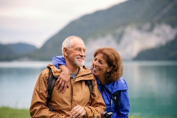 A senior pensioner couple hiking by lake in nature, resting.