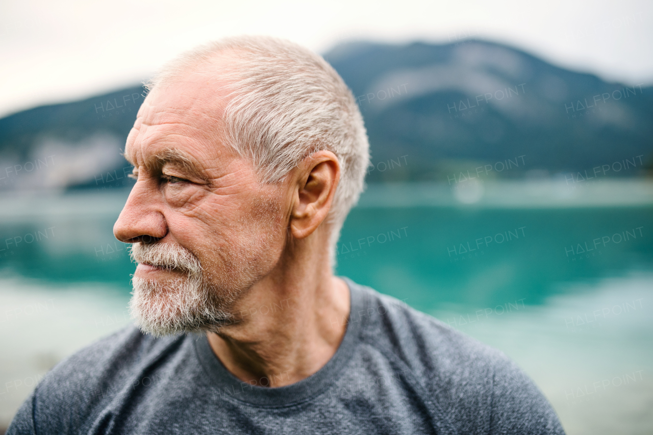 A close-up portrait of senior man pensioner standing outdoors in nature. Copy space.