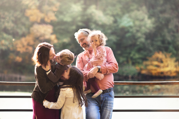 A beautiful young family with small children on a walk in autumn forest, resting.