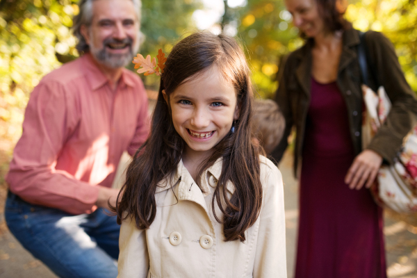 Portrait of small girl with family on a walk in autumn forest.