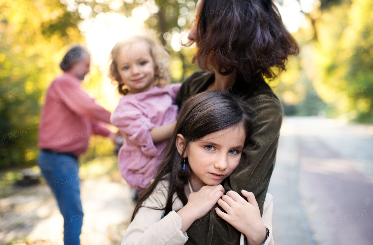 A beautiful young family with small children on a walk in autumn forest, having fun.