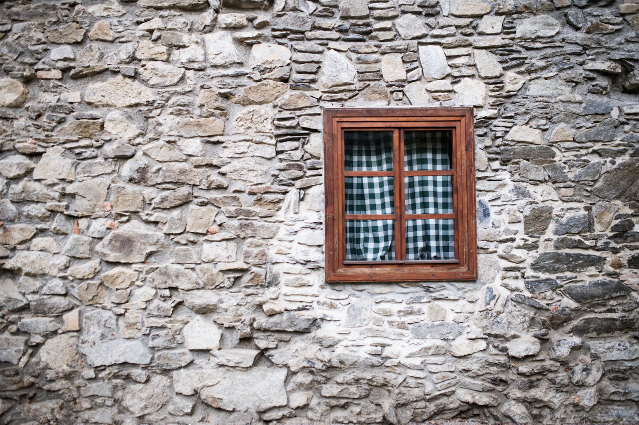 A wooden window in stone wall of old house. A copy space.