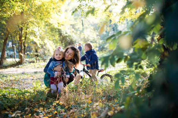 A beautiful young mother with small twins on a walk in autumn forest.