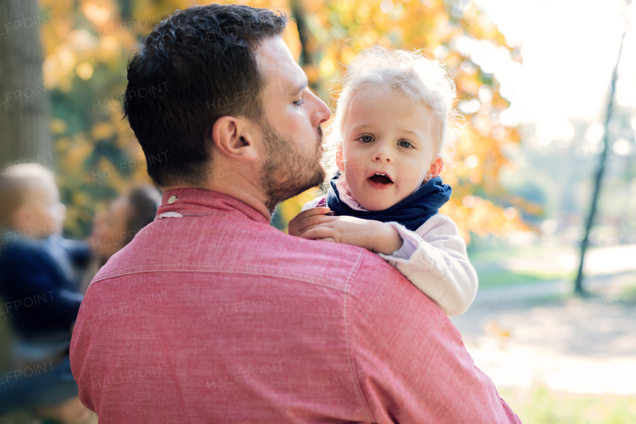 Unrecognizable father with small daughter on a walk in autumn forest.