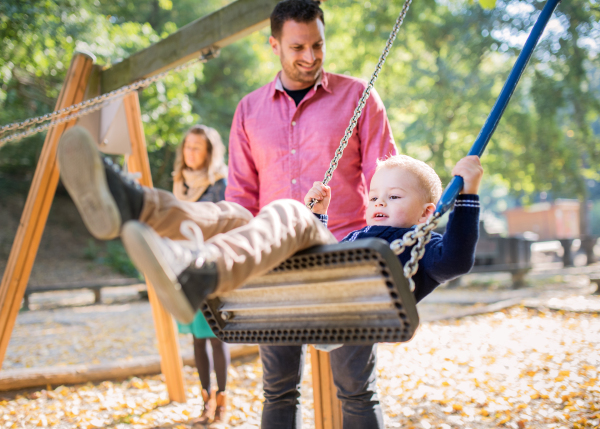 A beautiful young family with small son playing on playground in autumn.