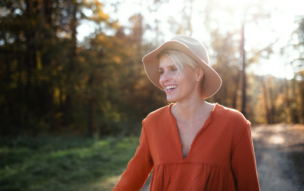 Portrait of happy young woman on a walk in autumn forest, walking.