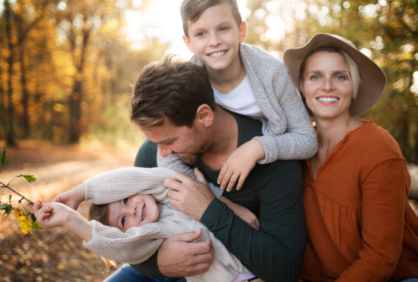 A beautiful young family with small children on a walk in autumn forest, having fun.