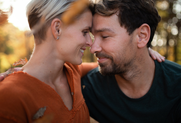 Close-up of young couple in love on a walk in autumn forest, hugging.