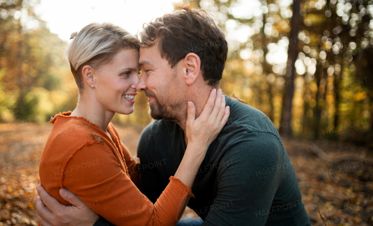 Close-up of young couple in love on a walk in autumn forest, hugging.