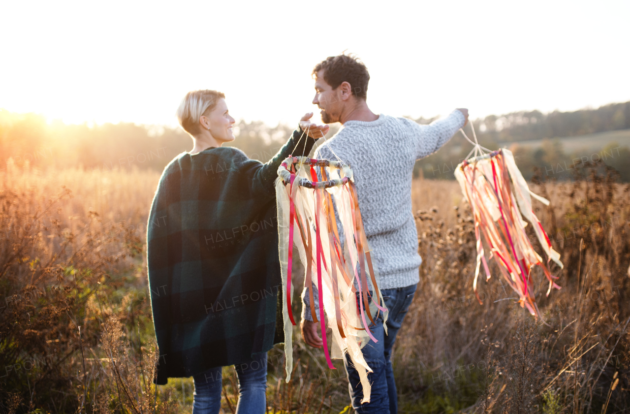 Rear view of young couple in love on a walk in autumn forest, holding hand ribbon kites.