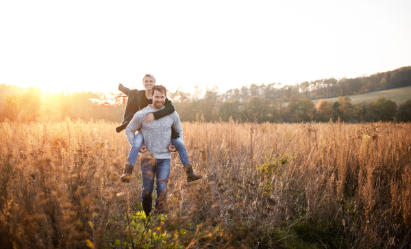 Happy young couple in love on a walk in autumn forest, holding hand ribbon kites.