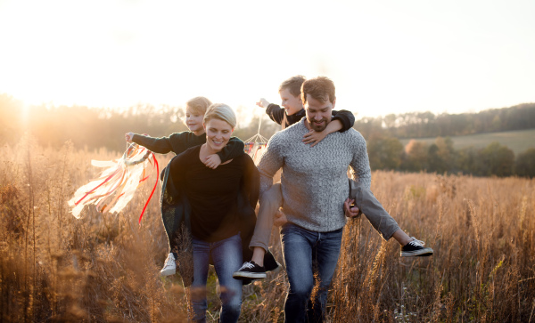 A beautiful young family with small children on a walk in autumn nature, having fun.