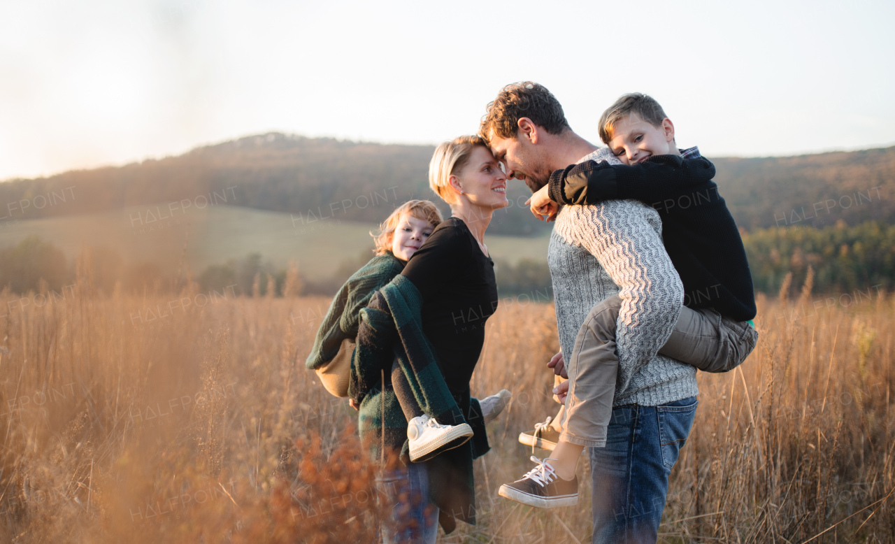 A beautiful young family with small children on a walk in autumn nature, having fun.